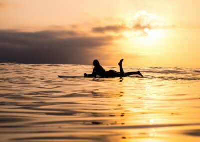 Surfbeach Encuentro 3 Surfergirl at sunset in the water on the furfboard